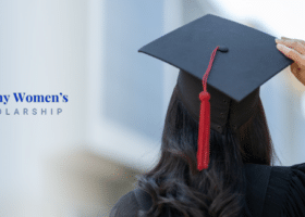 A woman in a graduation cap and gown with her back to us looking forward into her future.