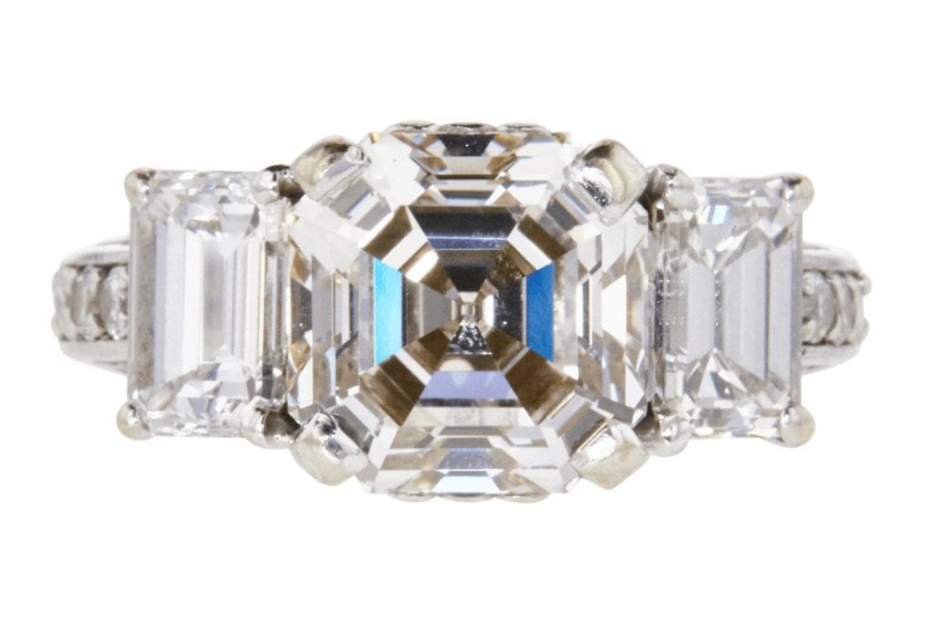 3.37 carat Asscher cut diamond at the center of 3-stone ring