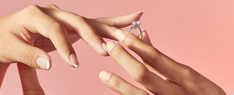 A woman's hands slipping on her engagement ring.