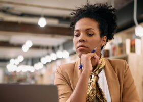 Female professor using laptop while doing a research at university library.