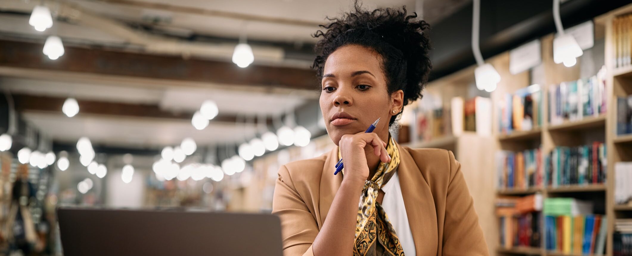 Female professor using laptop while doing a research at university library.